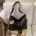 Detail of vintage brown leather tote bag with braided strap and cute plush bear charm - Coffee With Charms