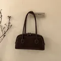 Détail d'un sac porté épaule en daim marron foncé avec surpiqûres blanches et double fermeture - Marron Châtain