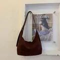 Detail of dark brown suede hobo bag featuring a wide shoulder strap and silver metal buckle - Brown
