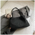 Detail view of black matte leather tote bag featuring white contrast stitching and shoulder straps - With Pendant / Black