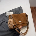 Detail of brown suede shoulder bag with silver chain strap and plush puppy charm accessory - With Pendant / Brown