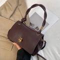 Close-up of vintage dark wine red handbag with gold clasp and twisted woven handle detail - Brown