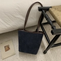 Detalle del bolso cubo grande de ante azul marino con ribete de cuero marrón en ambiente hogareño - Azul Crepúsculo