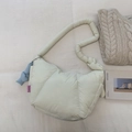 Close-up of cream quilted puffer bag with blue knot charm and soft texture detail - Off-white
