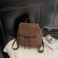 Detail of waffle-textured brown backpack with embroidery, drawstring, and flap closure - Coffee