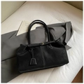Detalle de un bolso tote negro con costuras blancas en contraste y cierre de hebilla dorada - Negro