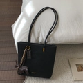 Close-up of black matte leather tote bag featuring gold lettering and cute animal charms - Black With Pendant