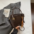 Detailed view of deep brown leather bucket bag with golden logo and wooden bead tassel - Coffee With Charms