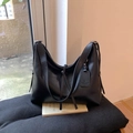 Dettaglio di una borsa tote in pelle nera con etichetta logo su un morbido cuscino - Nero PU