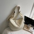 Dettaglio di una borsa in tela color crema con trama a nido d'ape e tracolla larga - Bianco