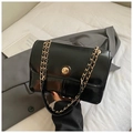 Close-up of black glossy leather flap bag with gold chain strap and metal rotary lock - Black