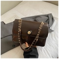 Detailed macro view of dark coffee glossy leather handbag with gold chain and round buckle - Brown
