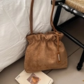 Details einer braunen Wildleder-Beuteltasche mit Faltenverschluss und Metallanhänger - Khaki