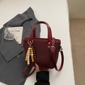 Détail d'un sac à main tissé bordeaux avec un gland en perles de bois et une poignée en cuir - Avec Pendentif / Bordeaux