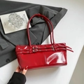 Detalle de bolso de hombro en charol rojo con correas de hebilla vintage sobre un blazer - Rojo