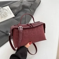 Detail view of burgundy leather pillow bag with subtle leopard texture and dual zippers - Red Leopard