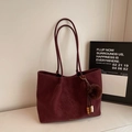 Macro detail of wine red suede tote bag with fur ball charm and golden logo - With Pendant / Burgundy