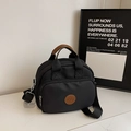Detail van de zwarte nylon tas met bruine lederen handvatten en een voorvak met ritssluiting - Zwart
