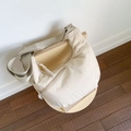 Detail of beige crescent crossbody bag with Wisdora embroidery on modern wooden chair - Off-white