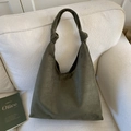 Detailed view of dark olive green tote bag featuring knotted strap handle on beige sofa - Green