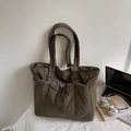 Detail of army green quilted tote bag with drawstring pocket on a white desk - Green