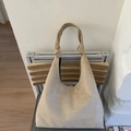 Detailed view of beige suede hobo bag with unique knotted handle on a modern chair - Khaki