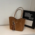 Dettaglio di una borsa tote in pelle marrone con logo dorato e ciondolo a forma di orsetto - Marrone con Ciondolo