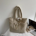 Close-up of quilted beige tote bag featuring elastic drawstring pocket and side compartments - Off-white