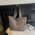 Detail of grey canvas tote bag featuring a metal logo, side zip pocket and woven label - Gray