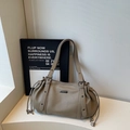 Close-up of taupe litchi grain leather shoulder bag with drawstring detail and metal logo - Khaki