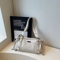 Detailed close-up of creamy white lychee grain leather tote with drawstring side and metal logo - Off-white