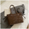 Gros plan sur un sac cabas vintage en daim marron avec anneaux dorés et finition élégante - Café sans Pendentif