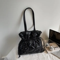 Detail of glossy black quilted tote bag with drawstring closure and chic lattice texture - Black