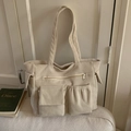 Detailed view of cream corduroy tote bag with multiple pockets and metal zipper - White