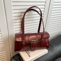 Detail of vintage dark red underarm bag with retro metal buckle on white books - Red