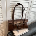 Close-up of vintage dark brown faux leather underarm bag with large aged metal buckle detail - Brown