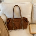 Detalle del bolso tote de ante marrón oscuro con asas de cuero y cremallera plateada - Marrón