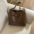 Close-up of vintage dark brown tote bag texture and golden buckle on a beige sofa - Brown