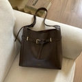 Close-up of deep brown leather tote bag with gold buckle detail on a cozy sofa - Brown