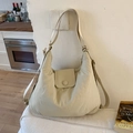 Detailopname van beige hobo-draagtas met klep-drukknoop en gestructureerde stof - Off-wit
