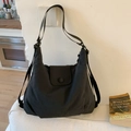 Close-up of black canvas tote bag with adjustable strap and button closure detail - Black