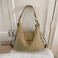 Detail view of khaki nylon crescent tote bag with wide strap and flap buckle on white fabric - Khaki