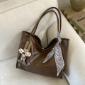 Makro-Detail braune Leder-Tote-Bag mit Seidenschal und Hasenanhänger auf einem Sofa - Braun mit Anhänger