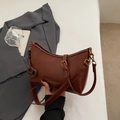 Detalle del bolso de hombro en cuero marrón oscuro con herrajes dorados y colgante - Marrón con Colgante