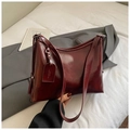 Detail shot of a burgundy oil-wax leather tote bag with stylish brand tag and buckle - Red