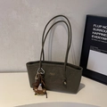 Close-up of olive green matte leather tote bag with plush bear charm and fashion label - Green with Charm