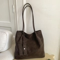 Detail view of large dark brown tote bag with smooth matte texture and mini charm pouch - Brown