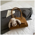 Detail einer braunen Wildleder-Unterarmtasche mit quadratischen Taschen und Plüsch-Hase - Braun mit Anhänger
