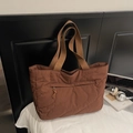 Detailopname van de donkerbruine gewatteerde shopper met golfstiksels en ritssluiting - koffiekleur
