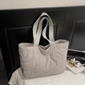 Detail of light grey quilted tote bag with wave stitching and wide ribbon handles - Gray